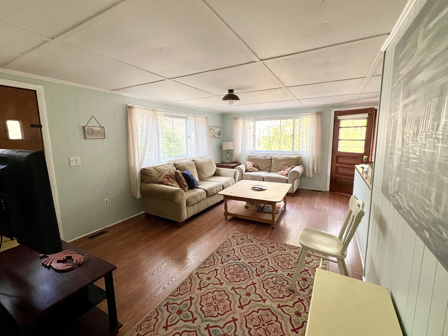 Sink into comfortable sofas in your bright living room, where natural light flows through large windows and warm wood floors invite relaxation.