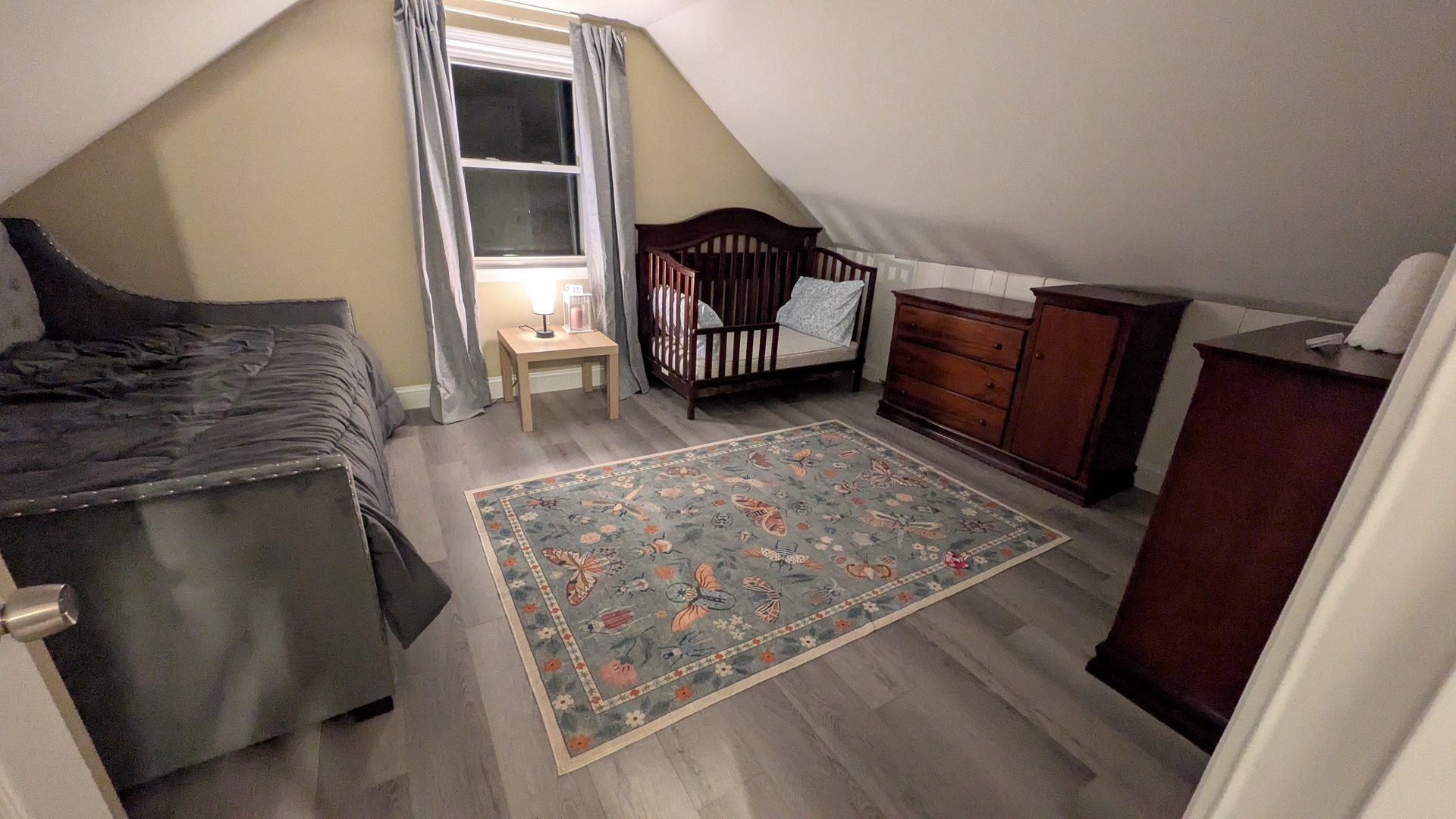 Your second floor bedroom features a queen trundle, baby bed, and warm natural light streaming through the window.