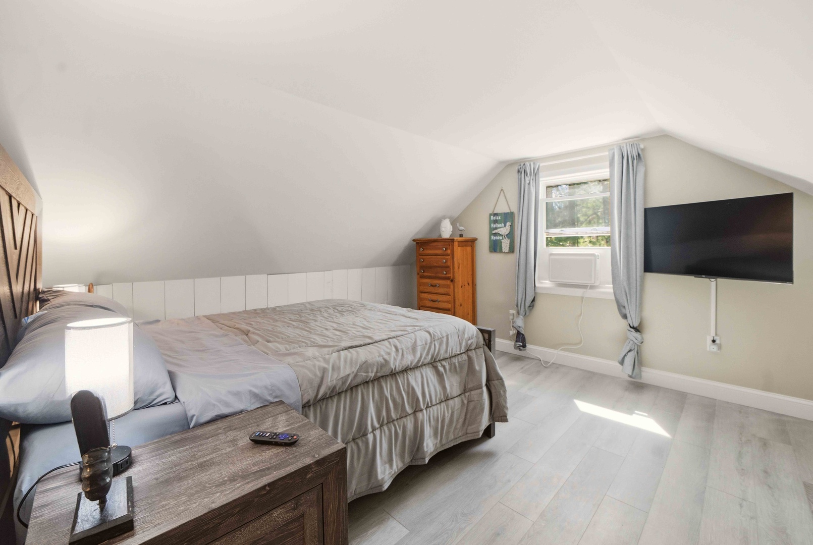 Unwind in this bright second floor bedroom where slanted ceilings create cozy charm and natural light streams through your private window.