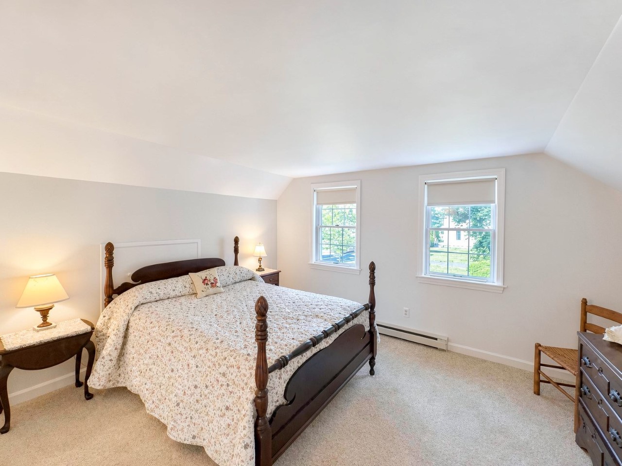 Your peaceful bedroom retreat features a cozy four-poster bed, soft natural light from dual windows, and warm furnishings that invite restful nights and relaxed mornings.