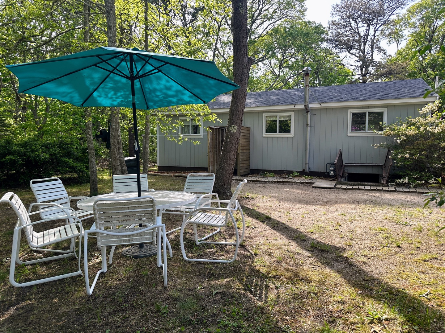 Relax under your private umbrella at the outdoor dining set, surrounded by towering trees that create a peaceful forest retreat.
