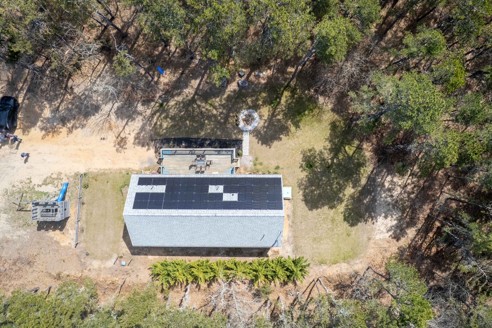 Aerial view of a secluded rental property nestled among native trees, featuring solar panels and natural forest surroundings for an eco-friendly getaway.