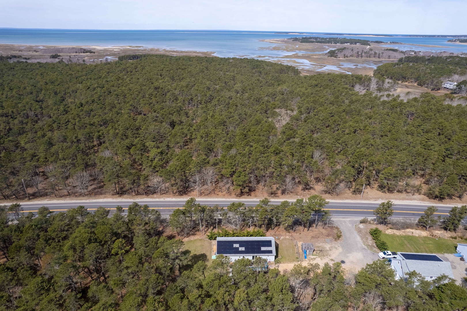 Aerial view showcasing the property's prime location between coastal waters and protected forest lands, offering peaceful surroundings.