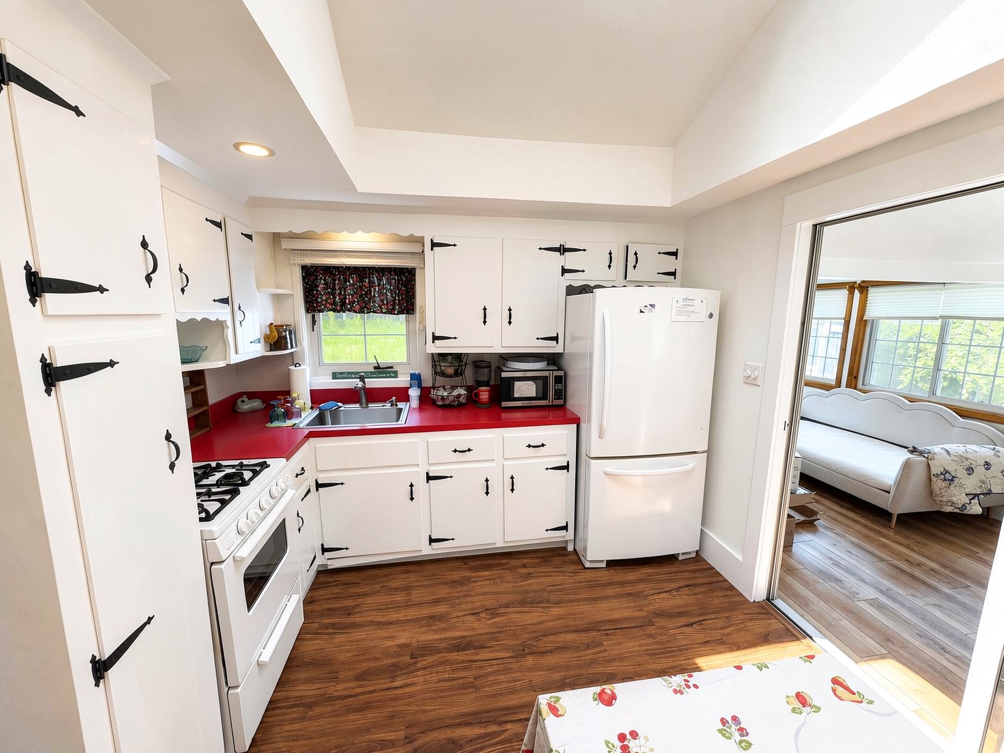 Your charming kitchen features classic white cabinetry with bold red countertops, a full-size refrigerator, gas stove, and microwave—everything you need to create homemade meals during your countryside getaway.