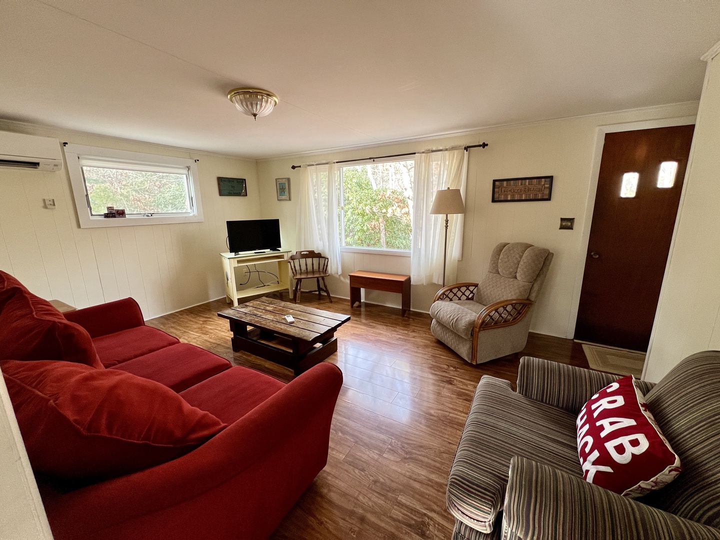 Sink into the plush red sofa and unwind in your spacious living room, where natural light streams through large windows creating a warm, welcoming retreat.