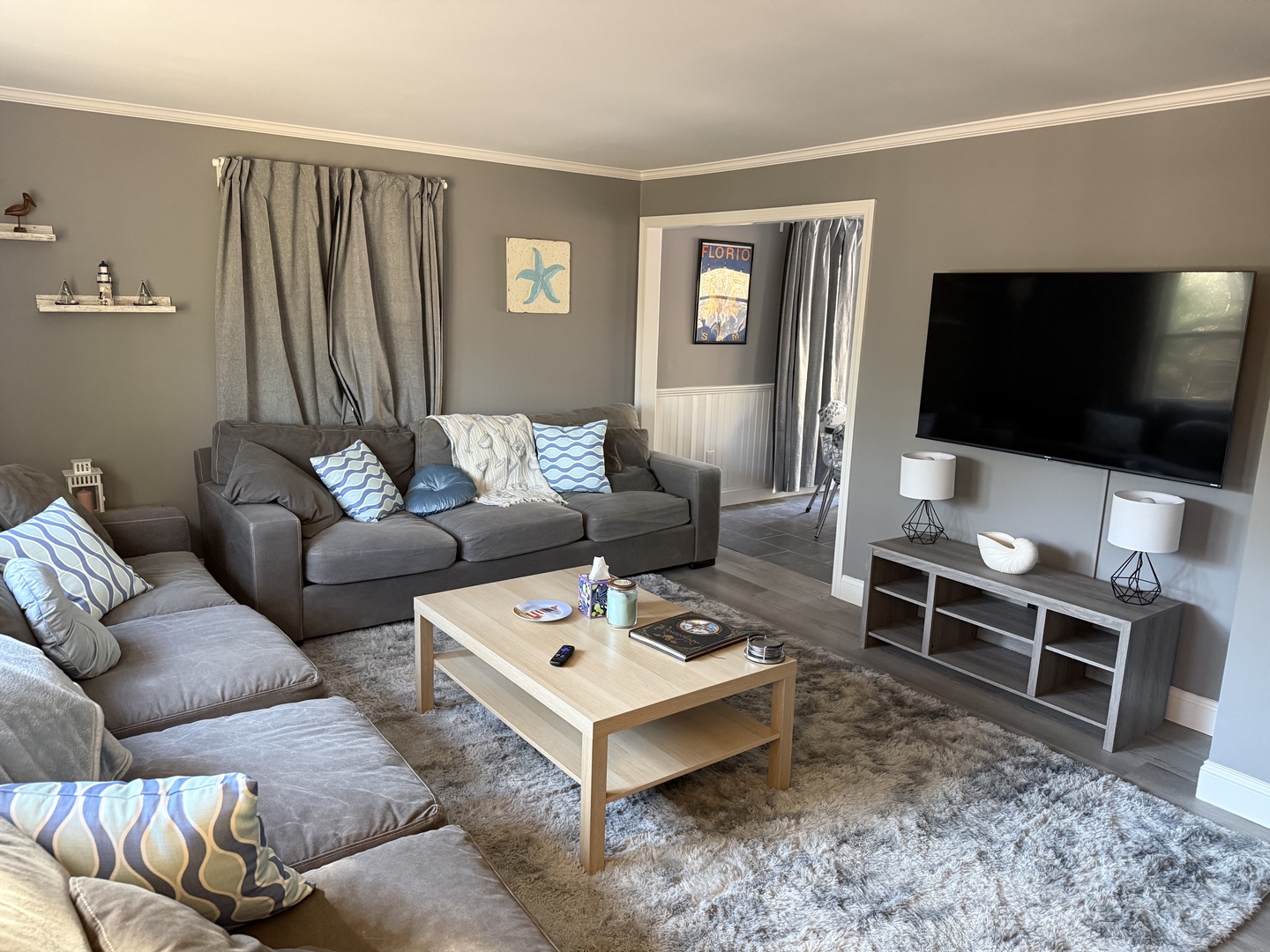 Sink into plush gray sofas and unwind in your bright, spacious living room with modern entertainment center and coastal touches throughout.