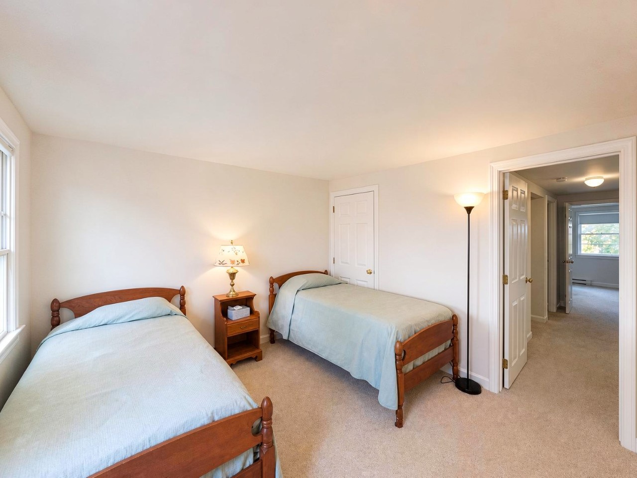 Step into your cozy twin bedroom with classic wooden beds and soft blue linens, where restful nights await after a day of exploring. Natural light and peaceful simplicity create your perfect retreat.