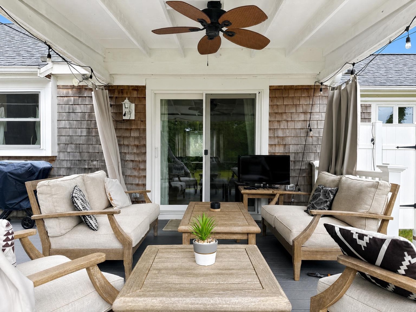 Covered outdoor living space,  with ceiling fan and comfortable seating.