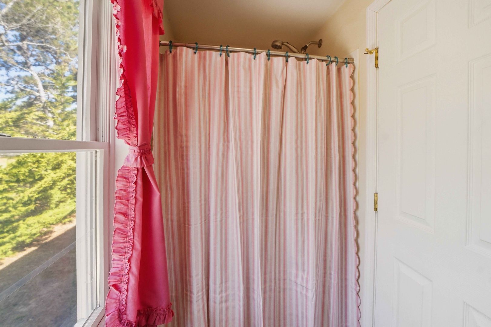 Step into your charming bathroom where pink striped curtains and cheerful red window treatments create a warm, cottage-like atmosphere.
