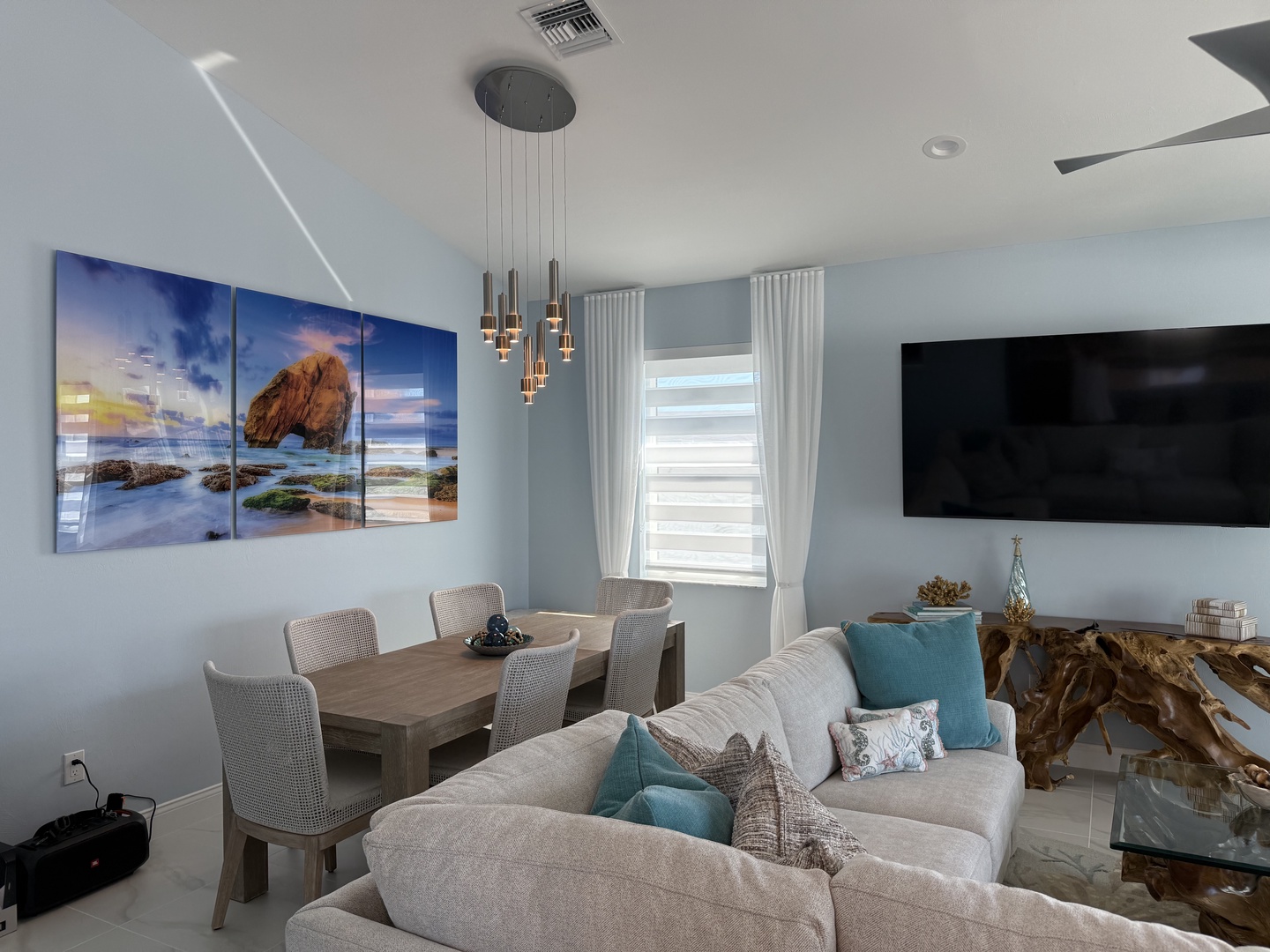 Unwind in your bright, coastal-themed living space where ocean artwork and soft blues create the perfect atmosphere for relaxing after beach adventures.