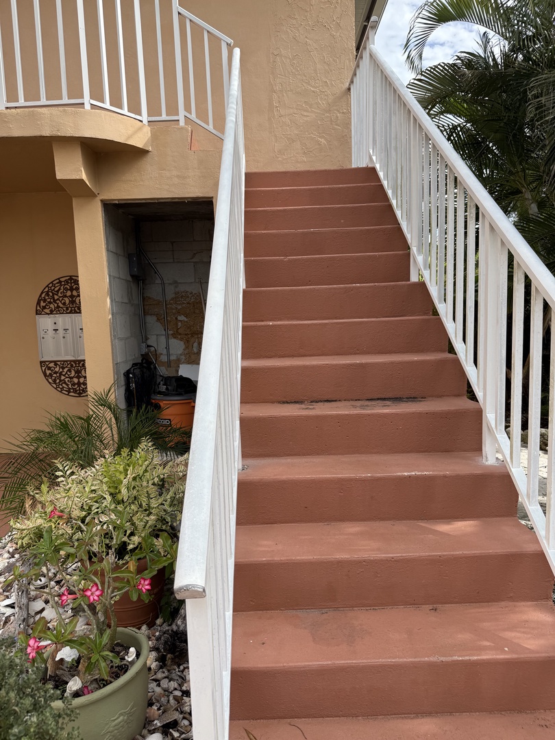 Your private covered terrace offers shade and relaxation, surrounded by lush tropical plants and colorful blooms.