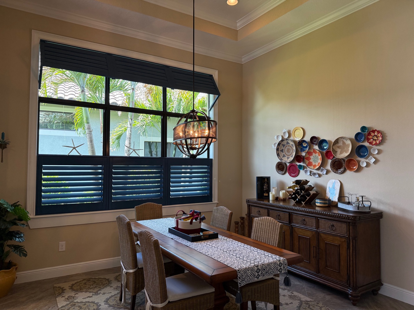 Your elegant dining space features warm lighting and vibrant wall art, perfect for memorable meals with tropical views through large windows.