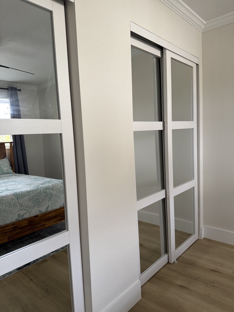 Your modern wardrobe features sleek glass panels and clean white frames, offering stylish storage space for all your belongings.