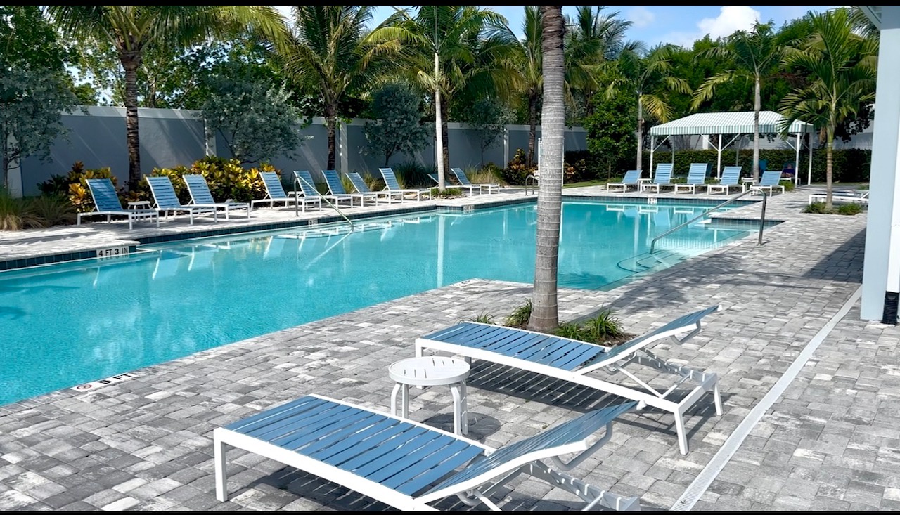 Spend your afternoons poolside under swaying palms, where blue lounge chairs invite you to relax and enjoy the Florida sunshine in this peaceful, resort-style setting.