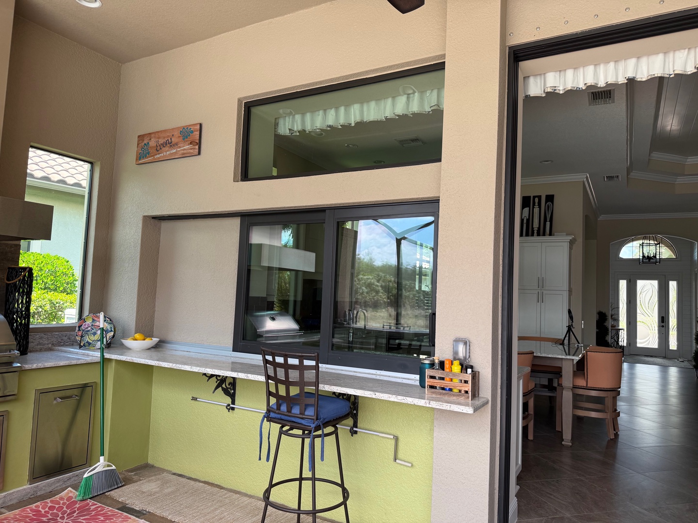 Your outdoor kitchen opens seamlessly to the main house, creating perfect flow for entertaining with modern appliances and cheerful island seating.