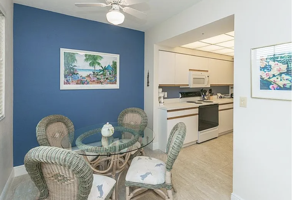 Step into your cozy dining nook with charming wicker seating and a peek at your well-equipped kitchen—perfect for relaxed meals at home.