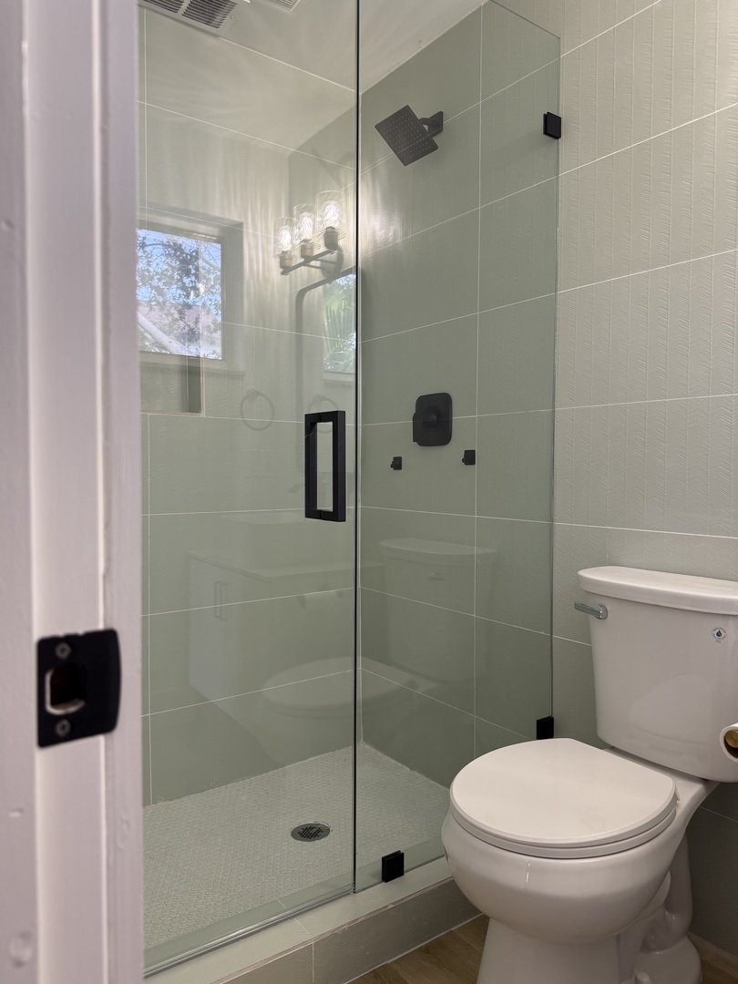 Private attached bathroom featuring a modern glass-enclosed shower with sleek tiling and contemporary fixtures for your refreshing getaway.