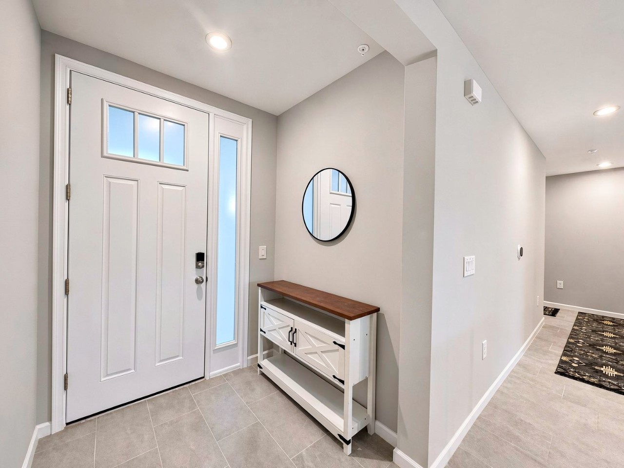 Step through the front door into a welcoming entryway with clean lines and soft, neutral tones. Natural light filters in through the side window, illuminating your arrival and setting a peaceful, inviting tone for your entire stay.