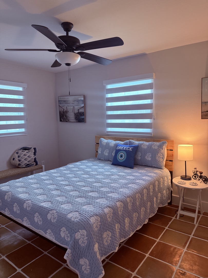 Sink into this soft, floral-patterned bedding where natural light filters through your window blinds. Your cozy retreat features warm tile accents, gentle bedside lighting, and a quiet space to unwind after exploring the area.