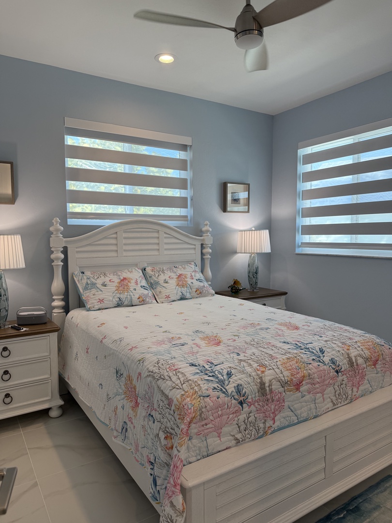 Drift off in your cozy bedroom with soft floral bedding and gentle natural light filtering through pristine blinds.