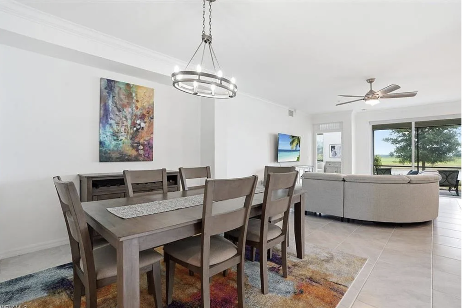 Gather with loved ones in this inviting dining space, where a bright, modern chandelier illuminates your meals and natural light streams in from the living area beyond.