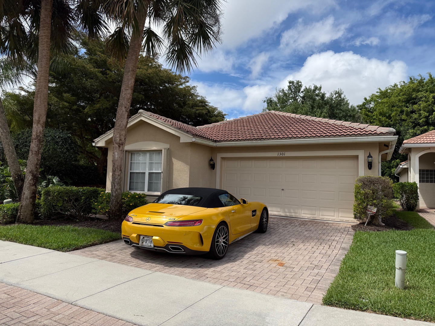 Elegant single-story home with tile roof in tropical setting, featuring palm trees and manicured landscaping.