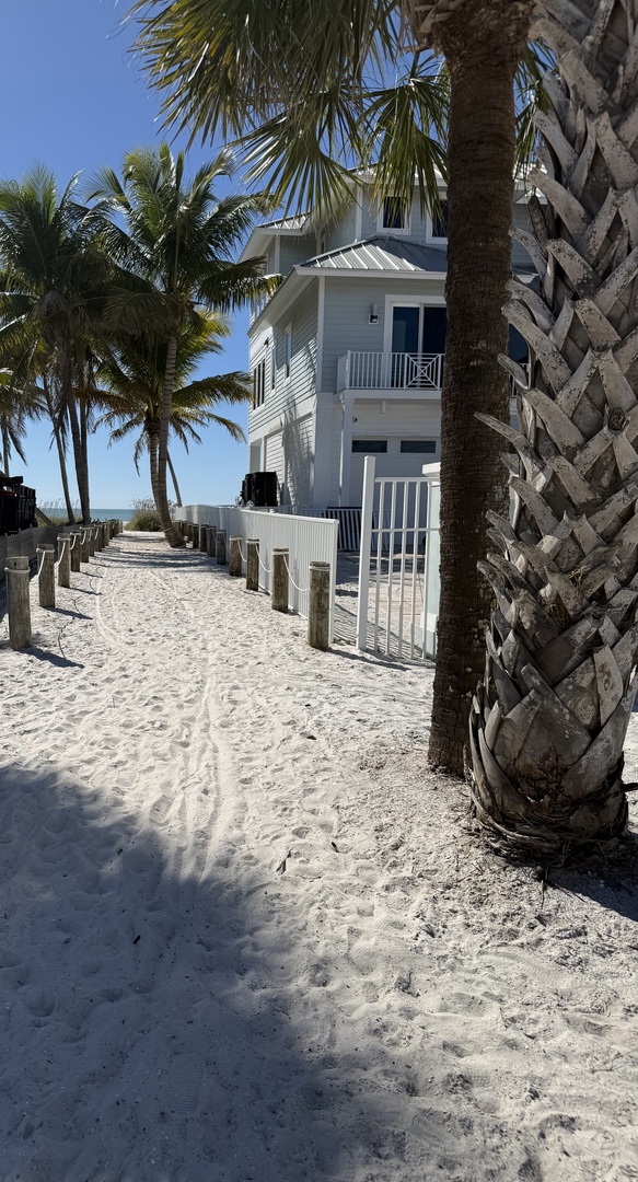 Beachfront property with pristine white sand and swaying palm trees creating a tropical paradise setting.