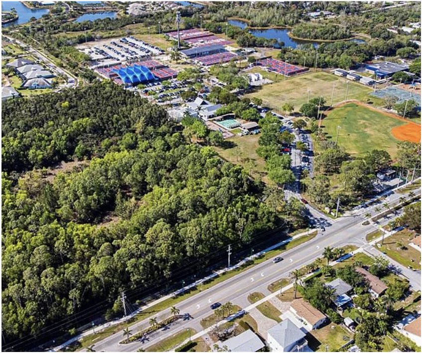 Aerial view of the surrounding neighborhood featuring tennis courts, baseball fields, recreational facilities, and natural waterfront areas nearby.