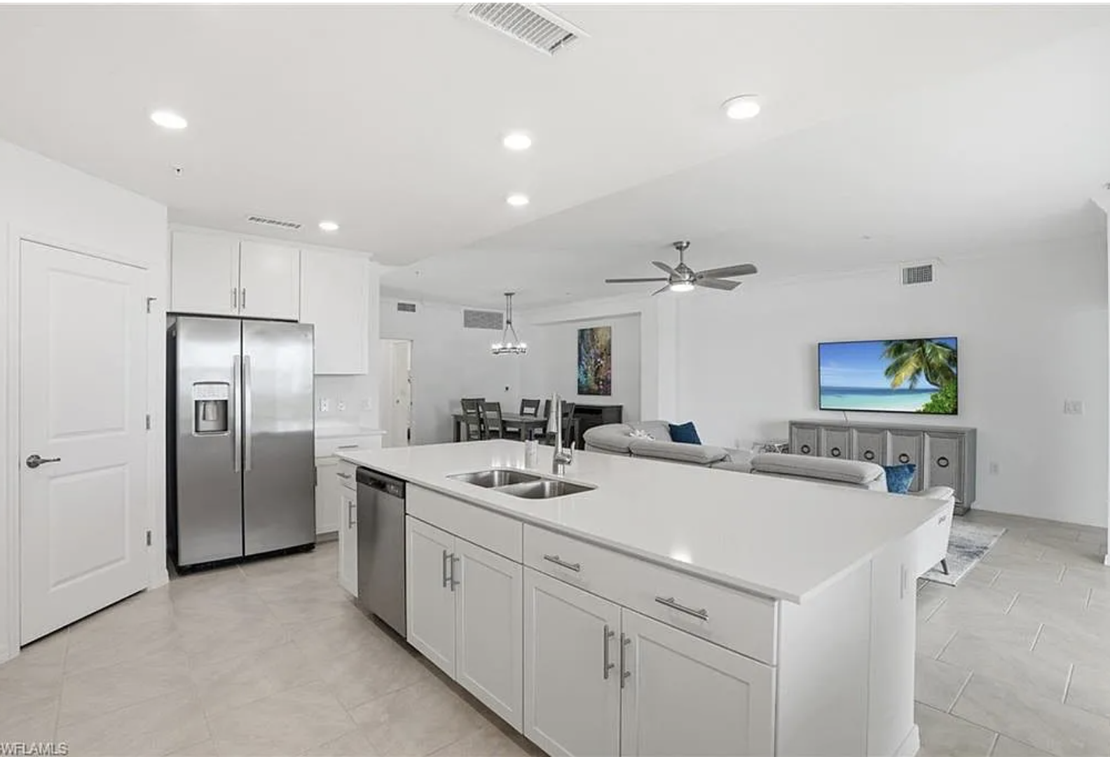 Step into a bright, modern space where sleek white cabinetry and stainless steel appliances set the stage for your culinary adventures, while an open flow invites you to gather with loved ones in the adjoining living area.