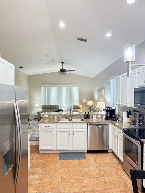Cook in your spacious kitchen featuring granite counters, stainless steel appliances, and bright overhead lighting that opens to the comfortable living area.