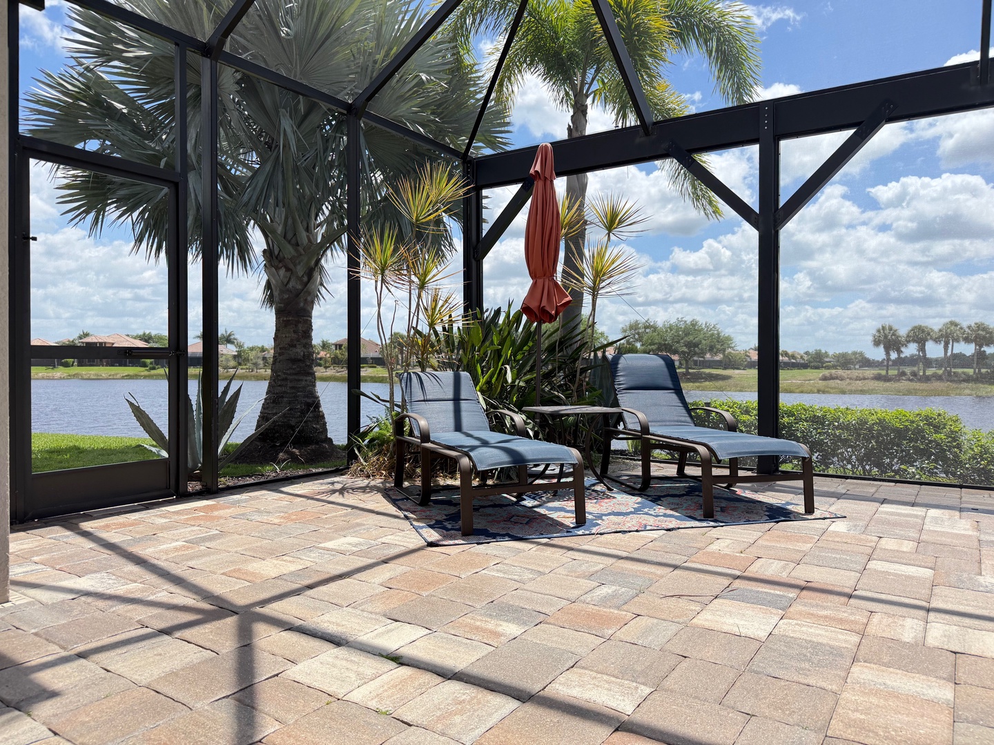 Relax in your private screened lanai with lake views, tropical palms, and comfortable lounge chairs for peaceful waterfront moments.