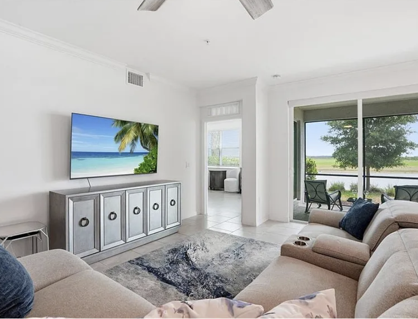 Sink into plush seating and let your gaze drift from the ceiling fan to the sliding glass doors that frame peaceful wetland views—your perfect spot for morning coffee or evening unwinding.