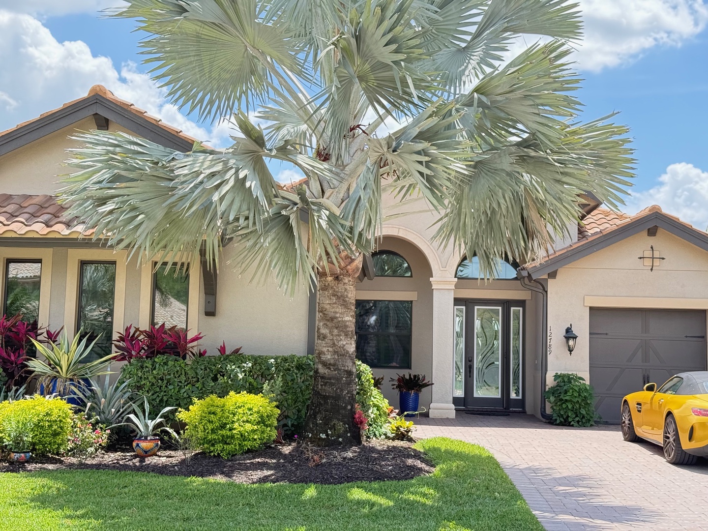 Mediterranean-style villa with tropical landscaping and elegant entrance, creating an impressive arrival experience in a desirable neighborhood setting.
