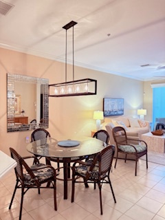 A welcoming dining area invites you to gather for meals, with a stylish table set beneath warm pendant lighting. Just beyond, the open kitchen and cozy living room await your everyday moments.