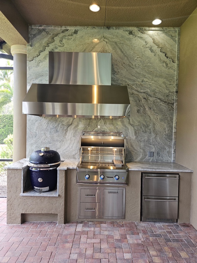 Your own outdoor kitchen awaits with a built-in grill, smoker, and sleek stainless steel appliances set against stunning natural stone—perfect for grilling under the sun and enjoying effortless outdoor entertaining.