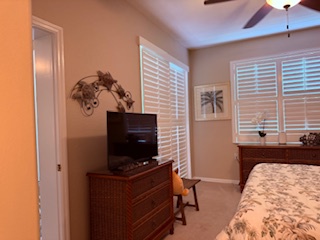 Step into your cozy retreat with elegant plantation shutters, ceiling fan overhead, and warm wood furnishings. Your flat-screen TV awaits for relaxed evenings in.