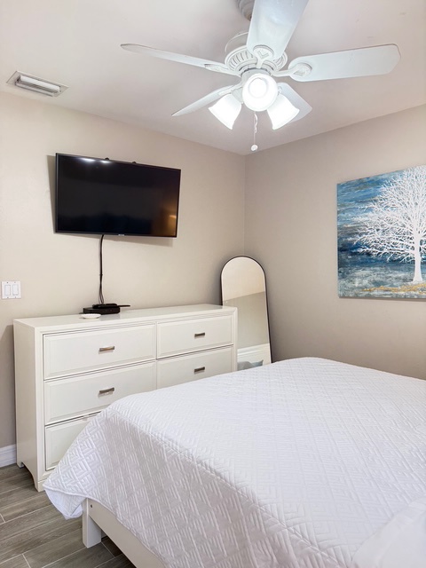 King Unwind in your peaceful bedroom featuring a plush bed, mounted TV for cozy nights, and elegant dresser storage for all your belongings.