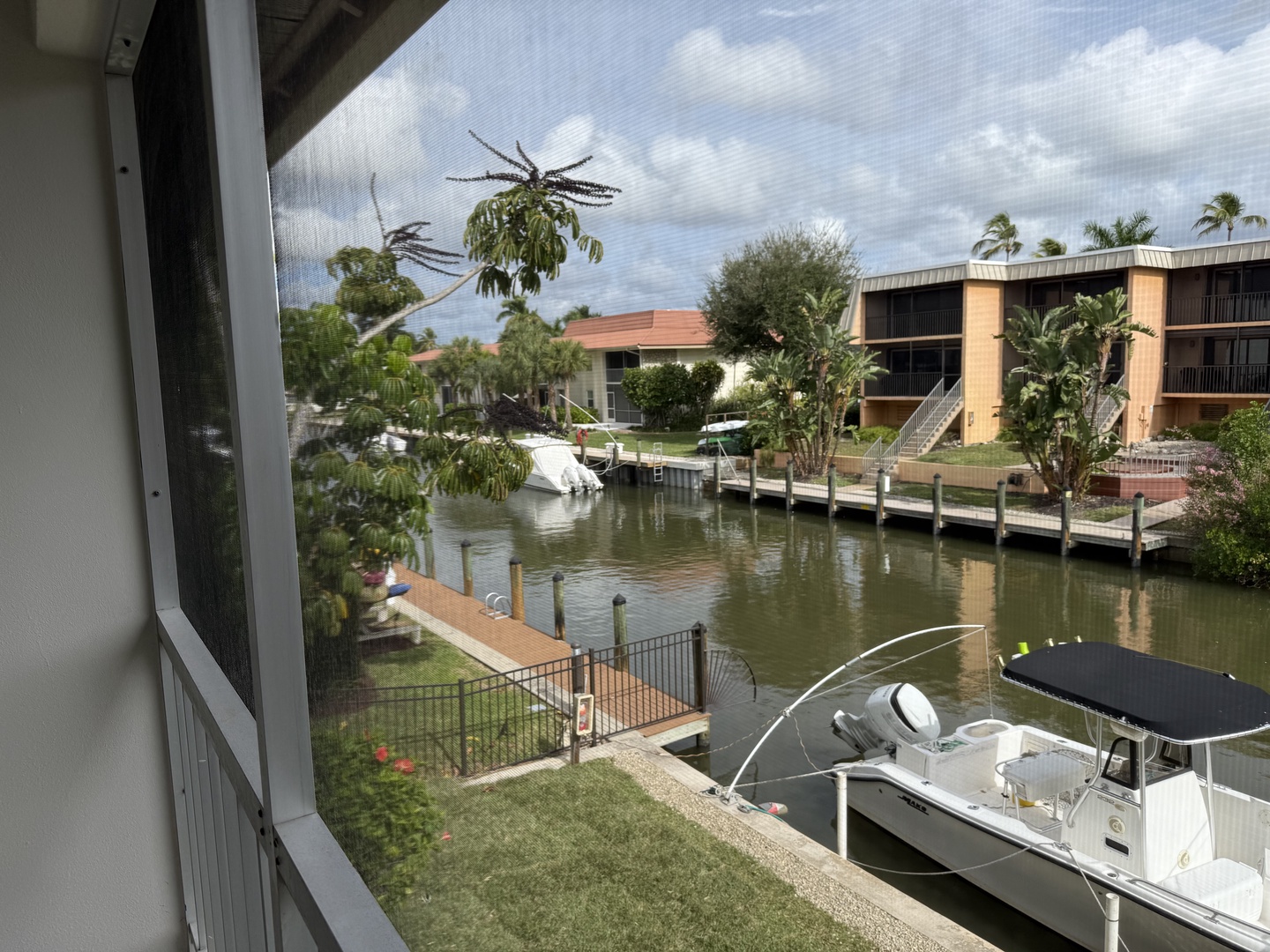 Wake up to tranquil waterfront views from your screened balcony, where boats gently dock and tropical palms frame the peaceful canal scene.