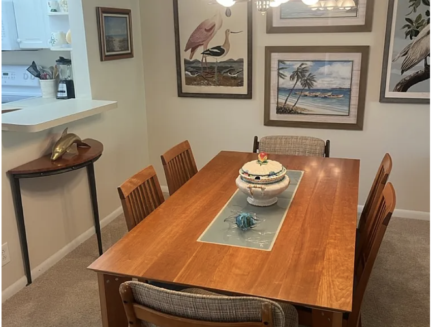 Your inviting dining space awaits, with warm wood furnishings, coastal artwork adorning the walls, and an open layout that connects to your bright, airy kitchen.