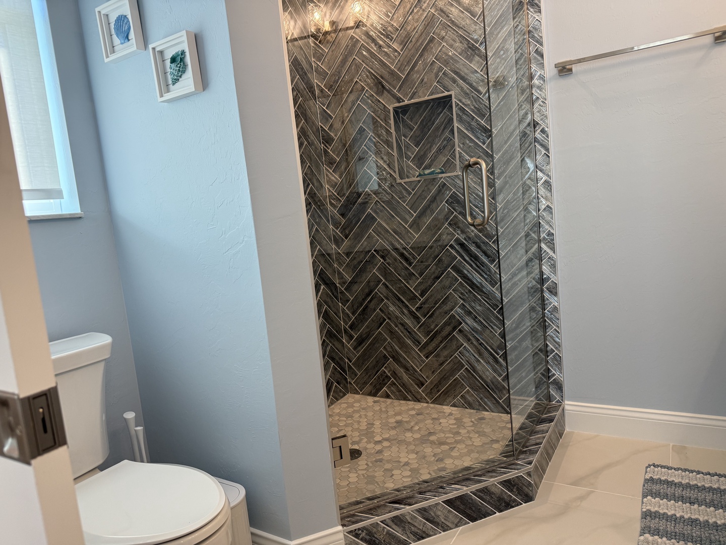 Unwind in your stunning bathroom featuring a luxurious walk-in shower with designer herringbone tile and glass enclosure.