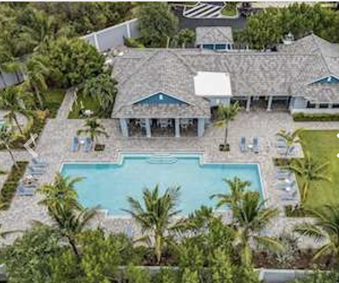 This stunning aerial view showcases the expansive pool surrounded by lush tropical landscaping. The beautiful property sits amid verdant gardens and mature palms, offering a private paradise setting.