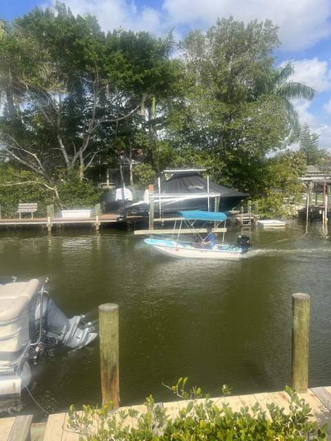 A tranquil waterfront property with private boat dock and lift, nestled along a calm canal surrounded by mature trees and lush Florida landscaping.
