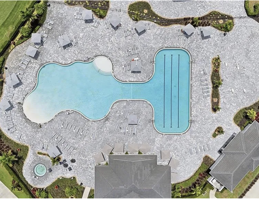 Aerial view of the property's distinctive lagoon-style pool and lap lane areas, surrounded by spacious sundecks and resort-style amenities.