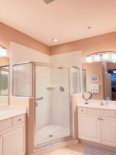 Your private bathroom features a spacious walk-in shower with glass doors, plenty of counter space, and warm lighting to start your day right.