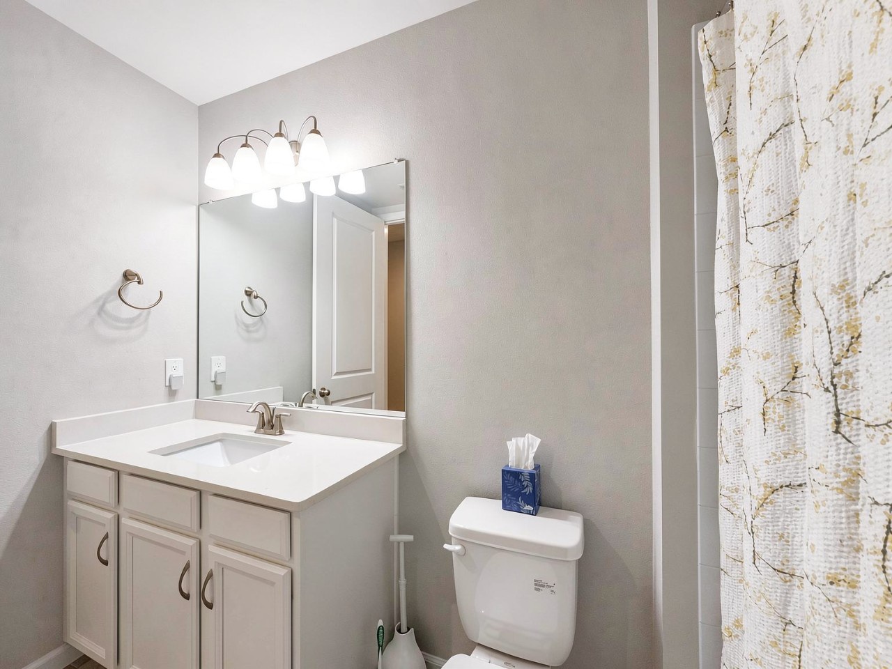 Freshen up in your private bathroom, featuring bright vanity lighting, a clean modern design, and thoughtful touches like fresh tissues ready for your arrival.