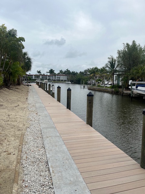 The property features a private dock on a calm canal surrounded by tropical landscaping and neighboring homes.
