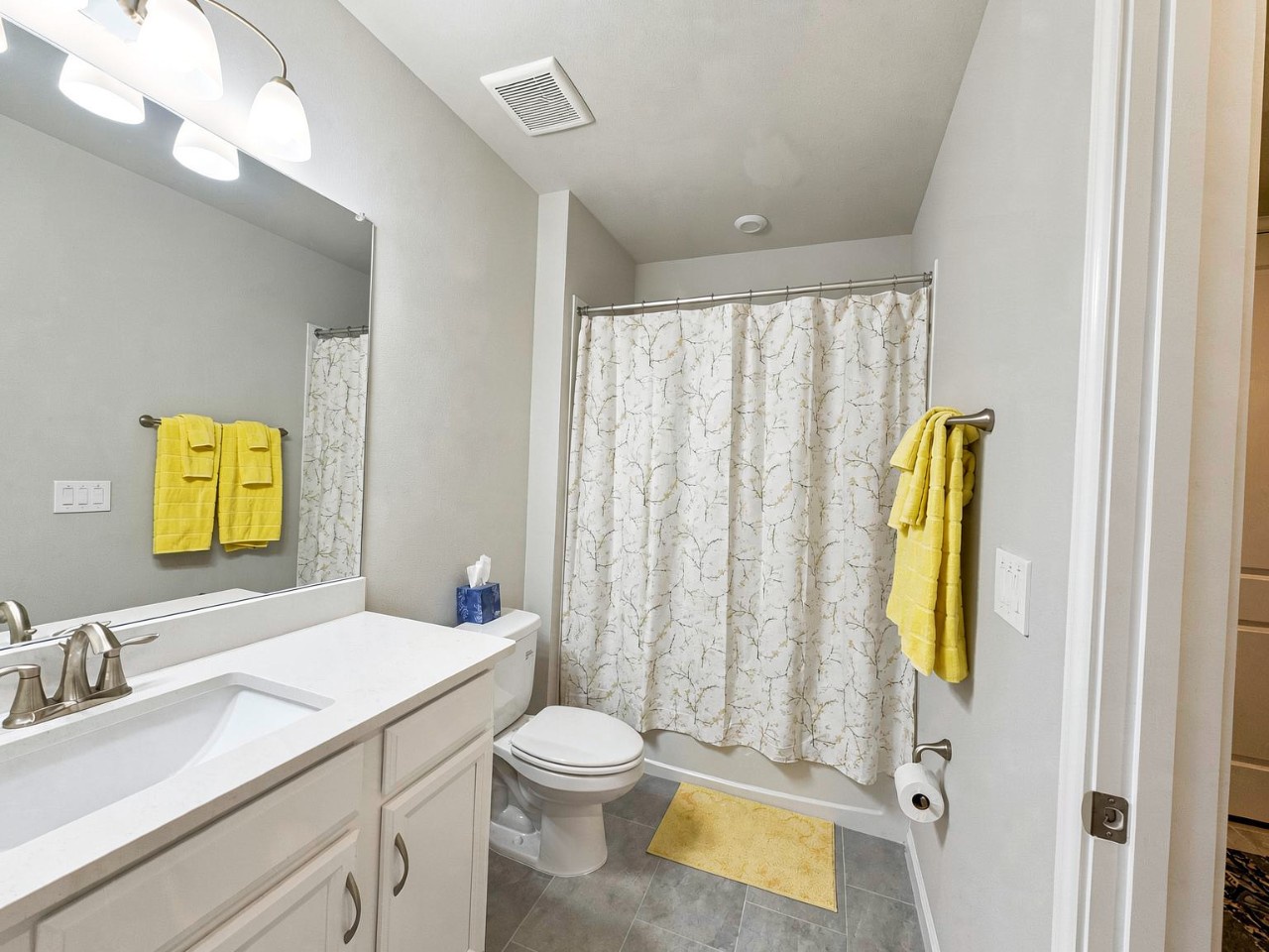 Step into your private retreat featuring soft gray tones and cheerful yellow accents that add warmth to the clean, modern design. Fresh towels and a bright shower await your arrival.