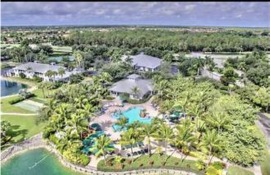 Aerial view showcasing the property and its waterfront location, surrounded by lush tropical landscaping and a sparkling pool area.