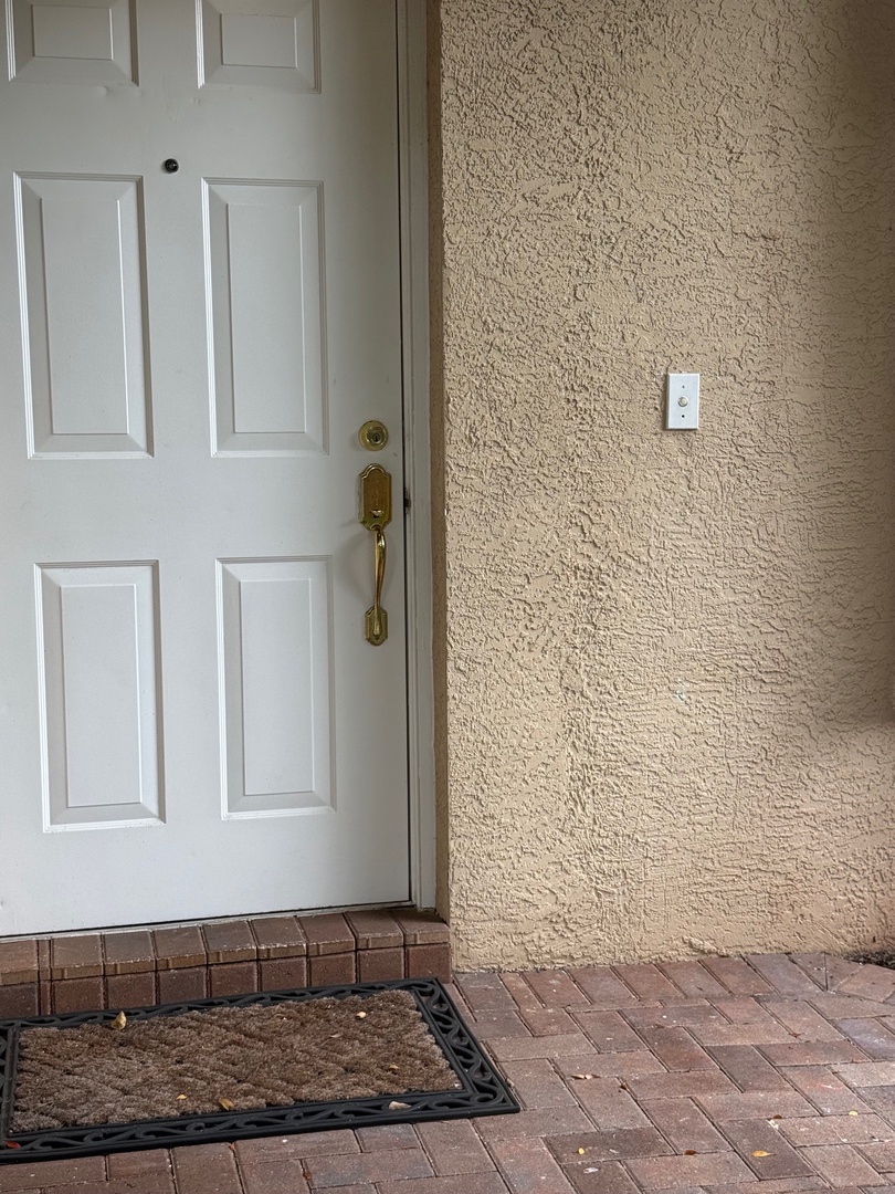 A welcoming entrance with classic white door and charming brick pathway leads to your home away from home.
