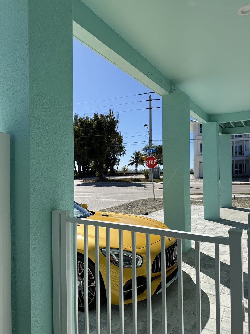 Street view from property balcony showing nearby parking and local neighborhood area with clear blue skies.